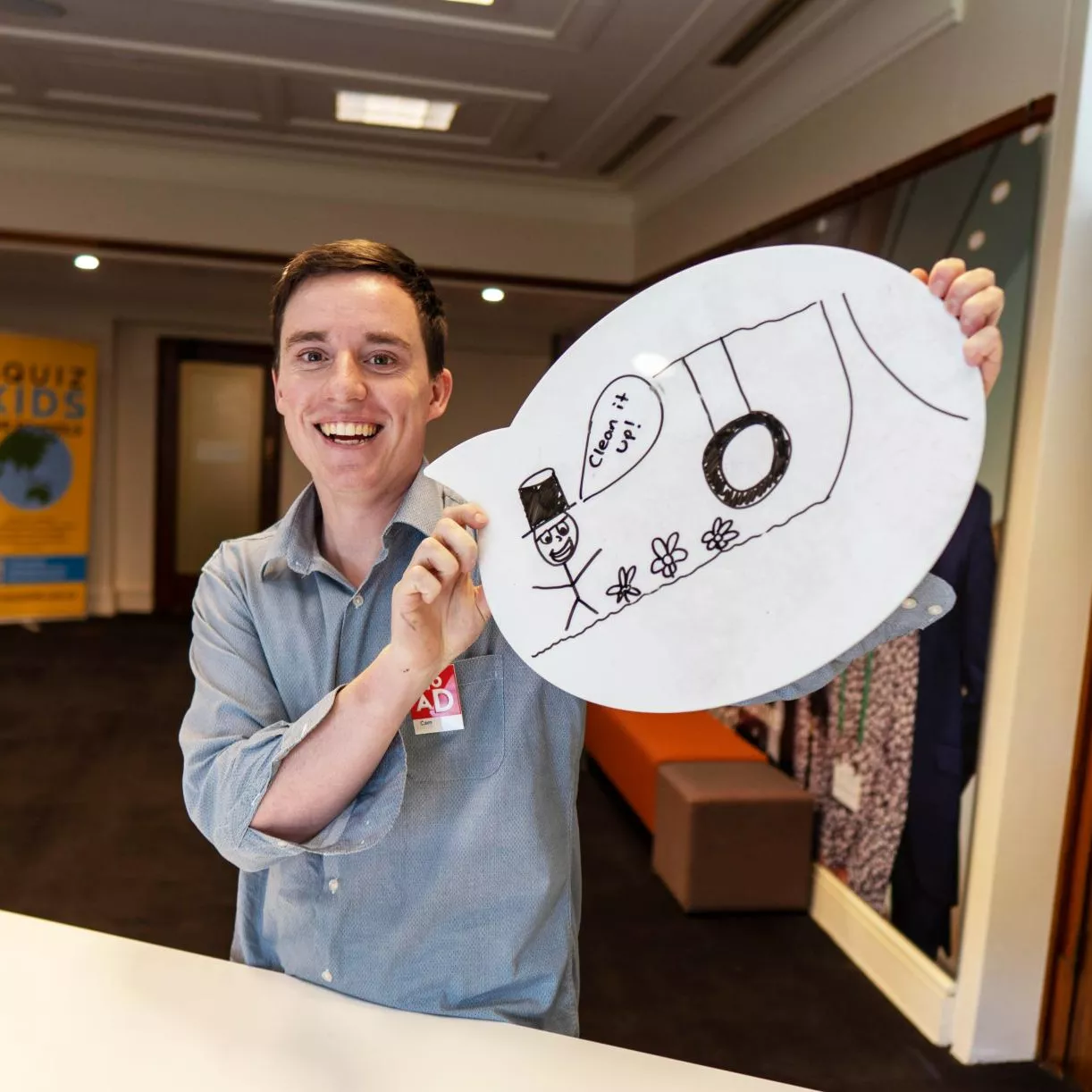 A person holds up a whiteboard speech bubble with a drawing on it.