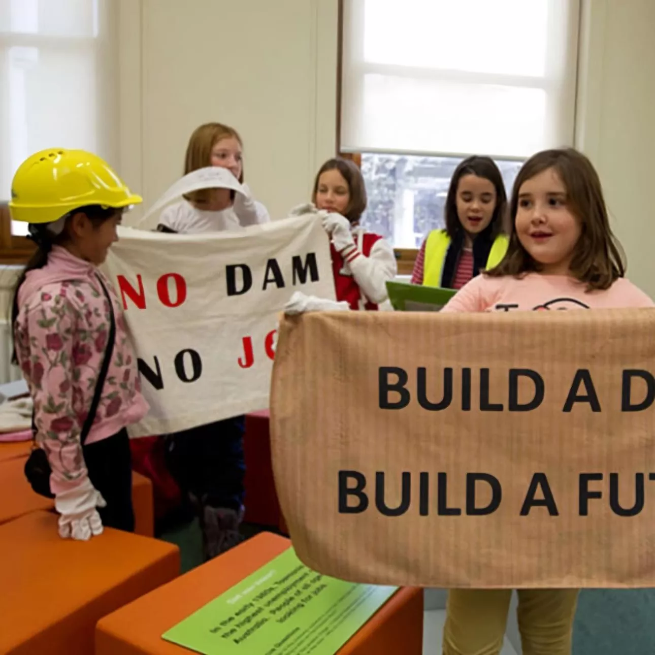 Primary school students hold up a sign which reads 'build a dam, build a future' inside Old Parliament House during an onsite program. 