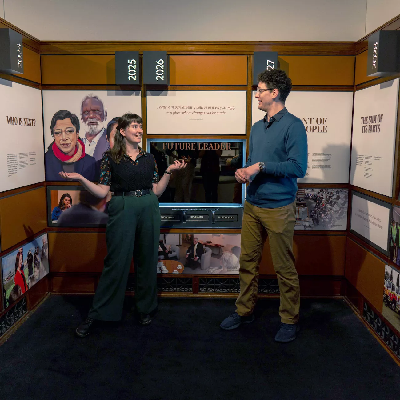 Photograph of two learning presenters standing in front of a wall with a mirror that says "future leaders"