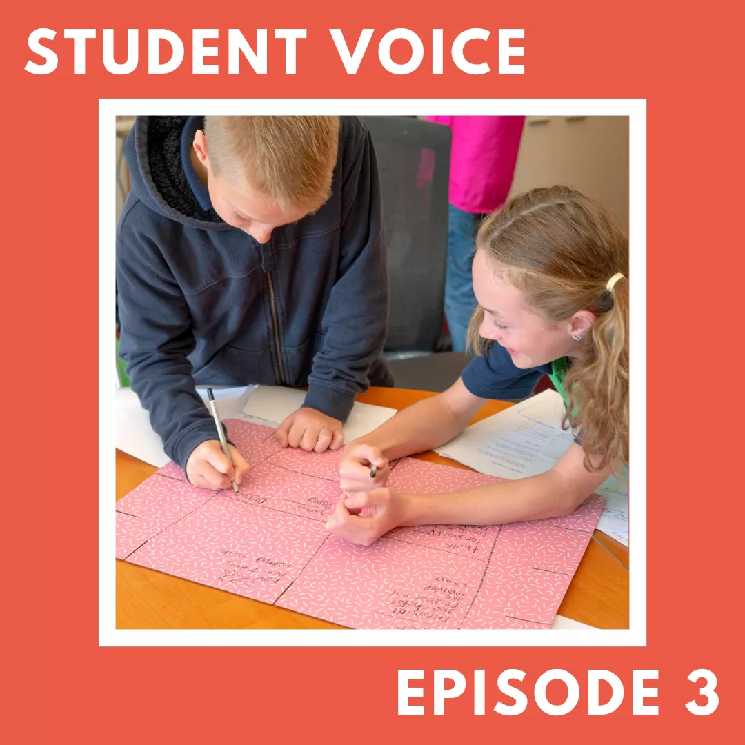 Two students in primary school write on a poster. 