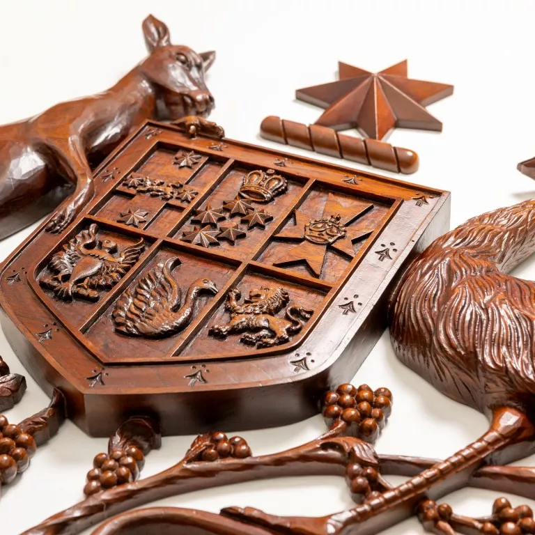 A close up of a wooden coat of arms with a kangaroo and an emu on either side of a shield. 