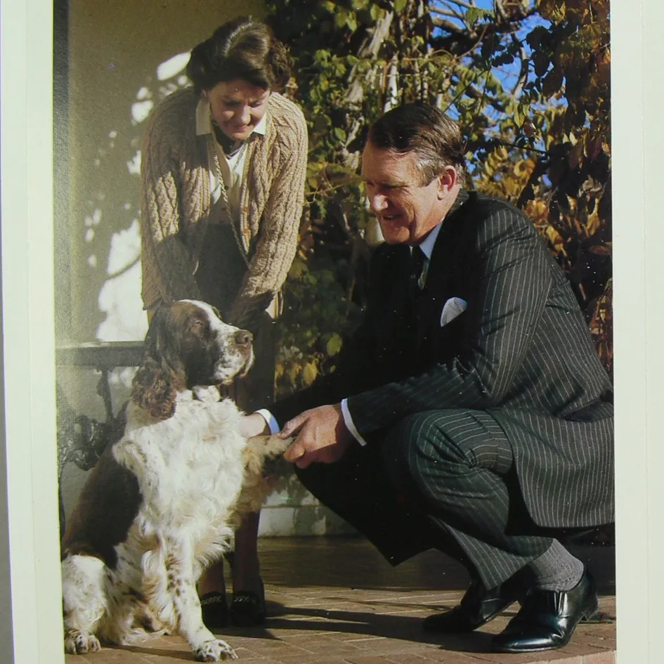 A Christmas card featuring a photo of Malcolm and Tamie Fraser with their dog, Droopy, a brown and white English springer spaniel.