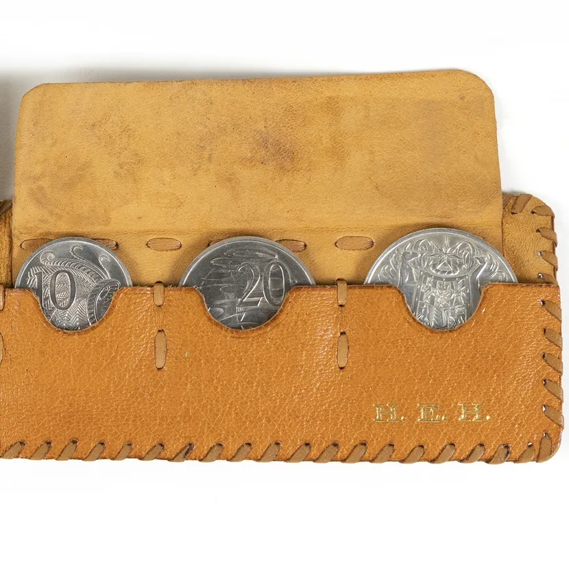 A leather pouch embossed with the letters H. E.H and holding a 1-cent, 2-cent, 5-cent, 10-cent, 20-cent and 50-cent coins