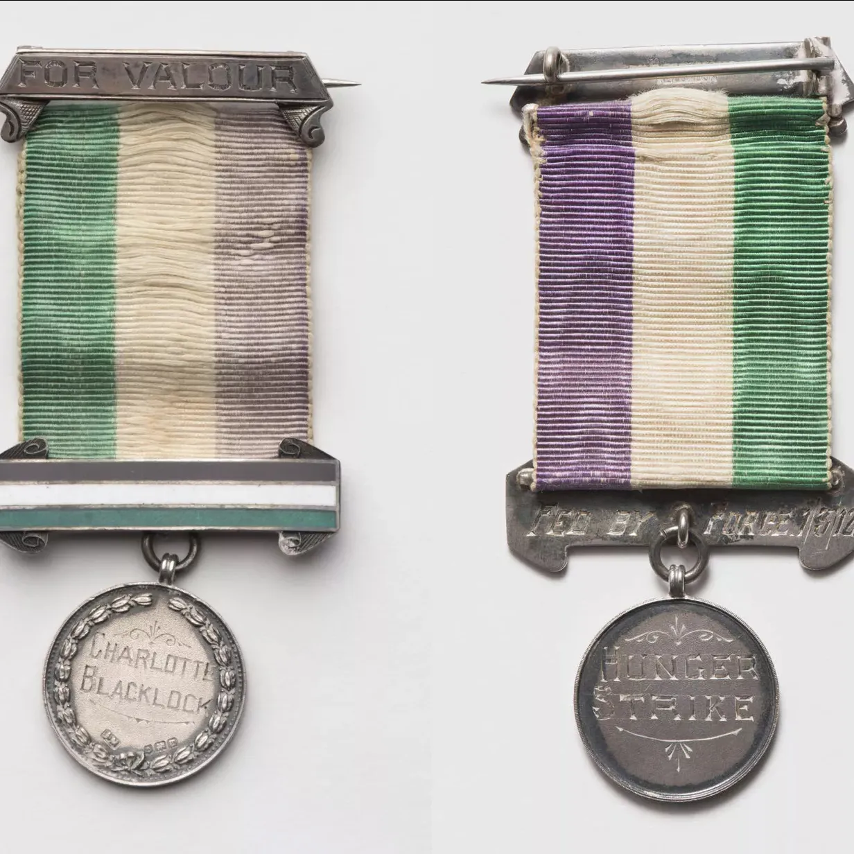 A round medal attached to a green, white and purple ribbon, etched onto the front the words 'For Valour' and 'Charlotte Blacklock', on the back 'Fed by force 1/3/12' and 'hunger strike'.