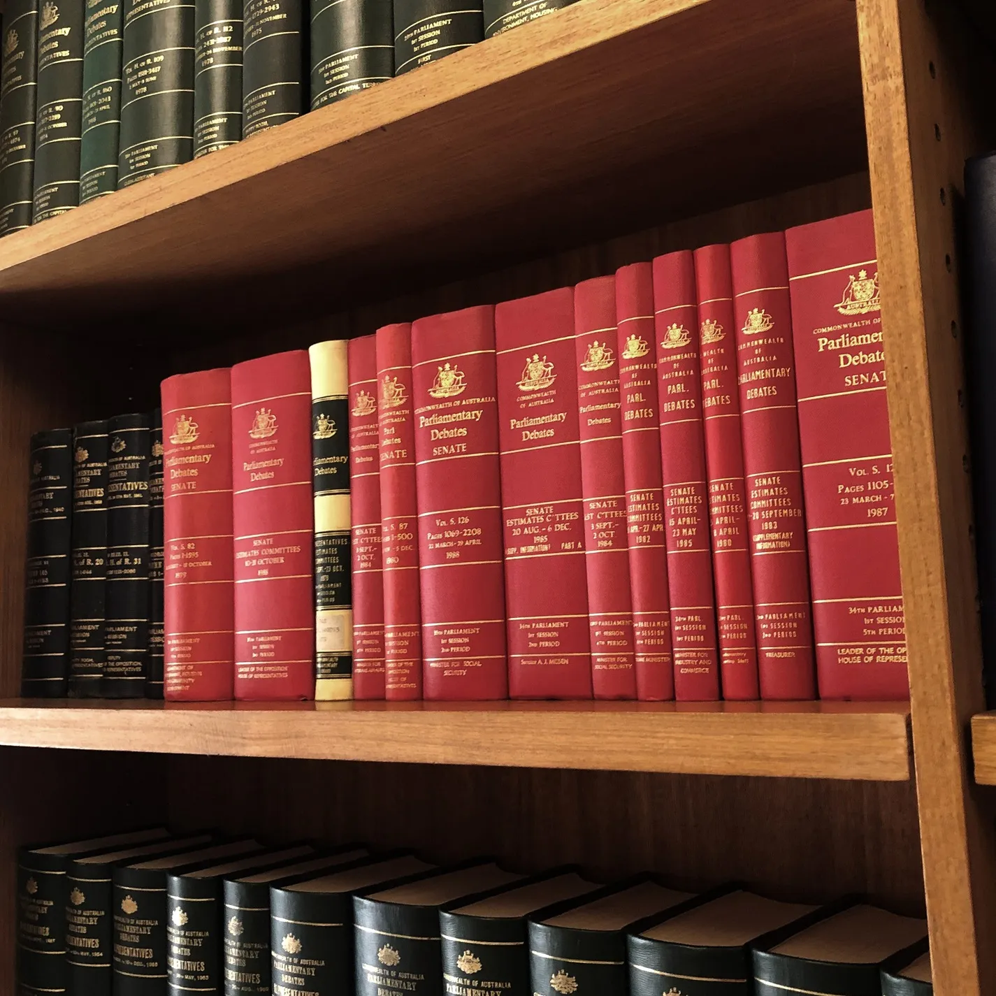 A row of red bound volumes on a shelf containing the proceedings of Senate Estimate committee hearings.