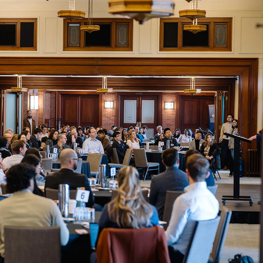 People seated at tables in the Member's Dining Room, facing a lectern where someone is giving a presentation.