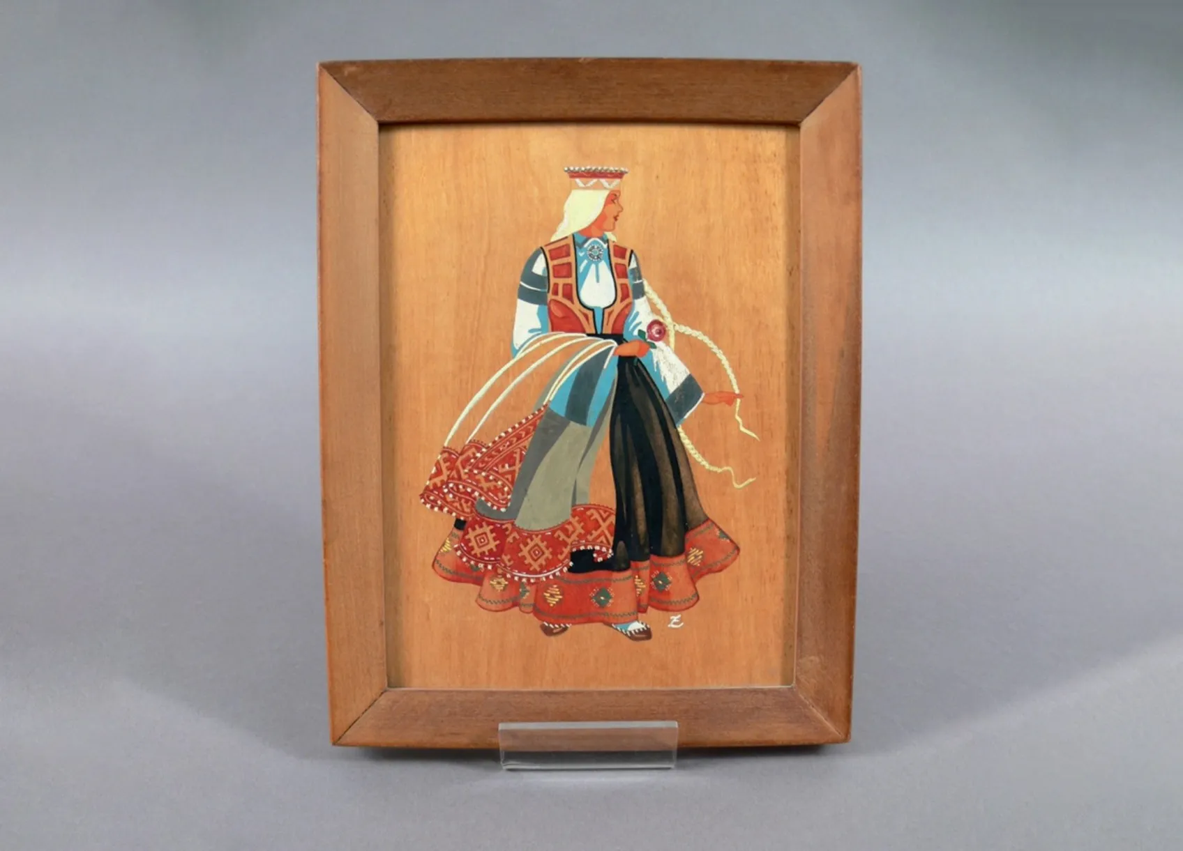 Painting on a wooden panel showing a woman wearing a traditional dress from Latvia.