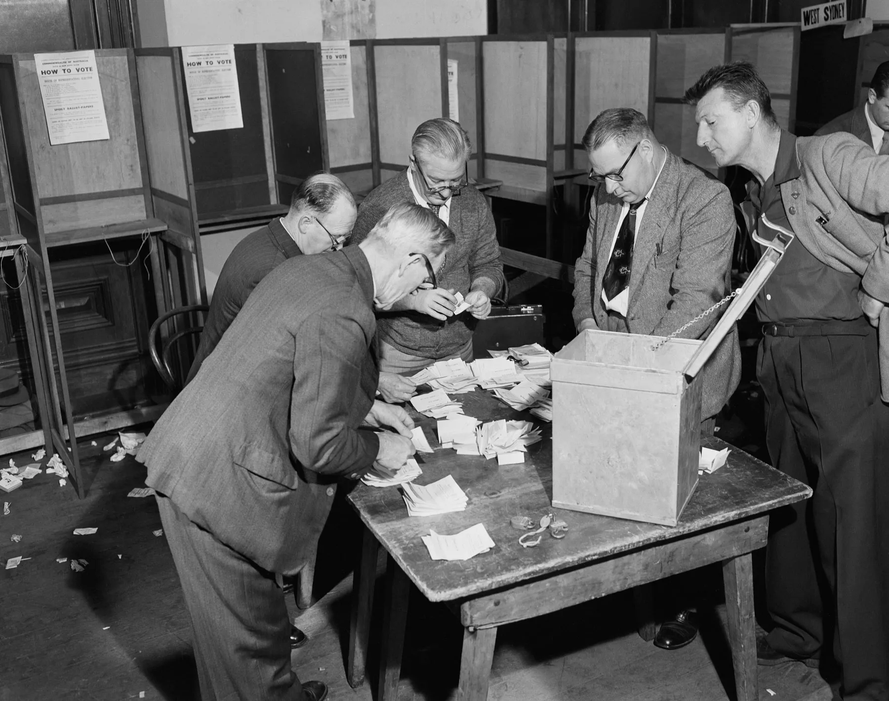 Men in suits count votes on a table in the Sydney Tally Room during the 1954 federal election.