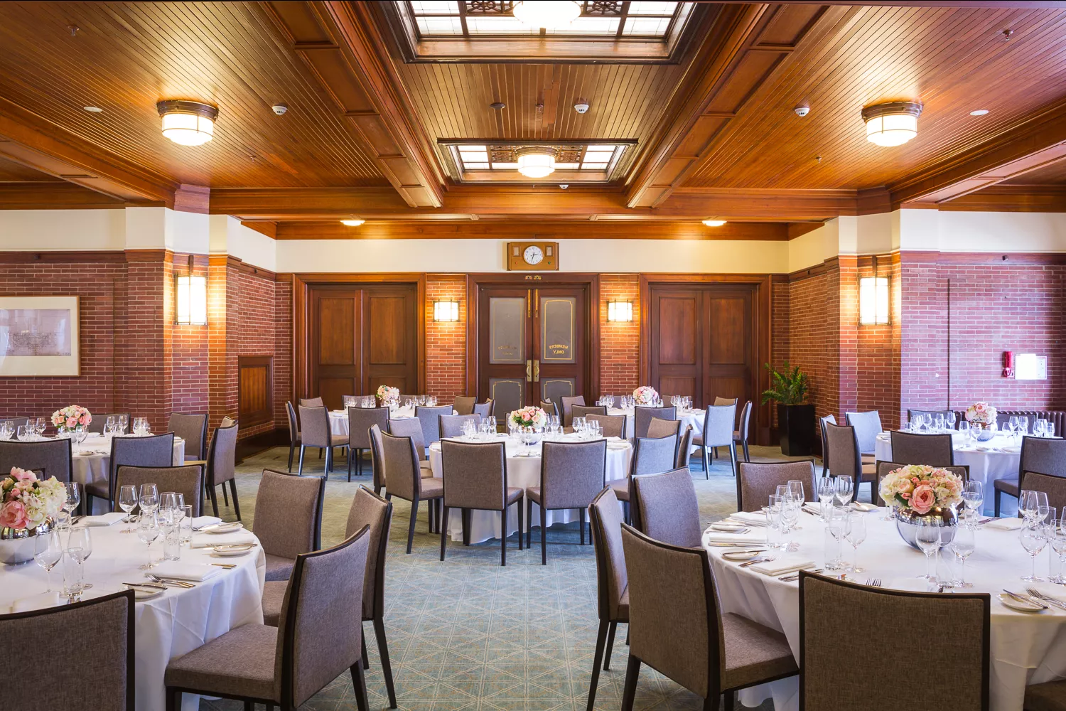 A room with a timber roof and many circular tables covered in white tablecloths. A room with a timber roof and many circular tables covered in white tablecloths.