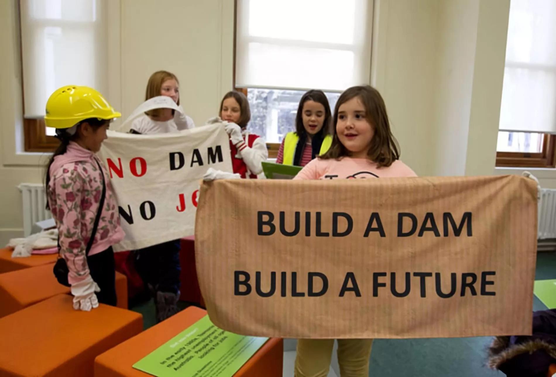 Primary school students hold up a sign which reads 'build a dam, build a future' inside Old Parliament House during an onsite program.