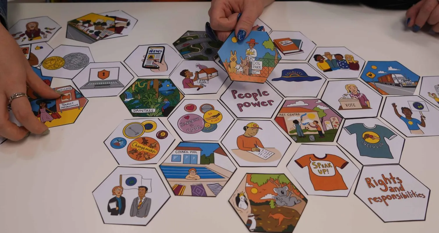 Hands move hexagon-shaped tiles featuring words and illustrations.