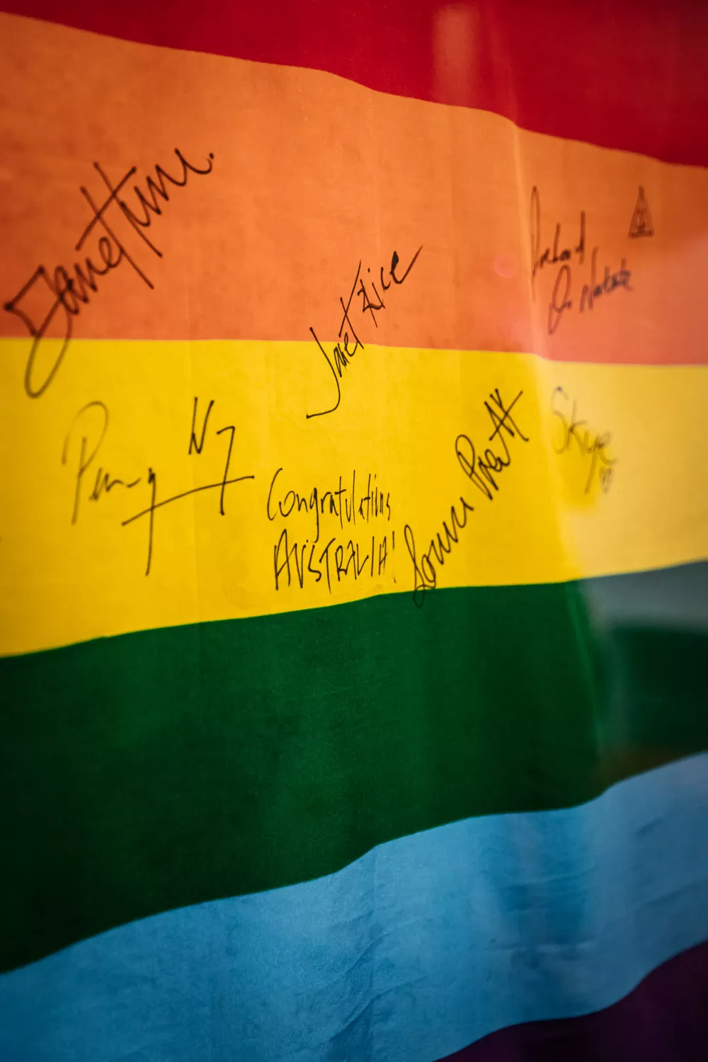 A close up of a rainbow flag covered in signatures. A close up of a rainbow flag covered in signatures.