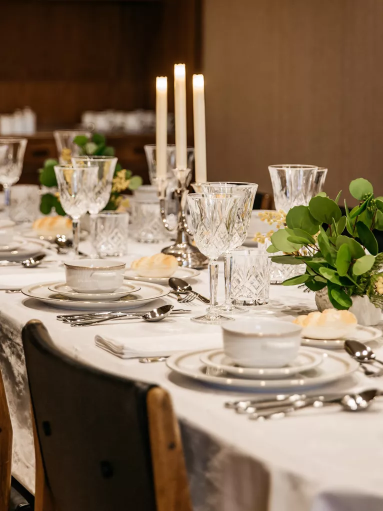 Be transported back to one of Joan’s dinner parties. A dinner table set up with china, white linens, silverware and white candles ready for a dinner party