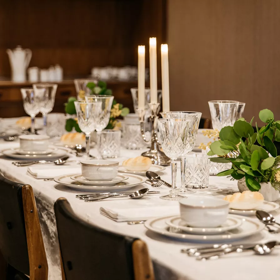 Be transported back to one of Joan’s dinner parties. A dinner table set up with china, white linens, silverware and white candles ready for a dinner party