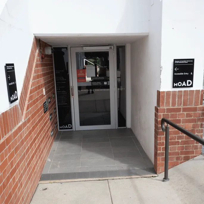 The entrance to a building with a glass and and a black and white sign with the words 'Accessible entry MoAD'. The entrance to a building with a glass and and a black and white sign with the words 'Accessible entry MoAD'.