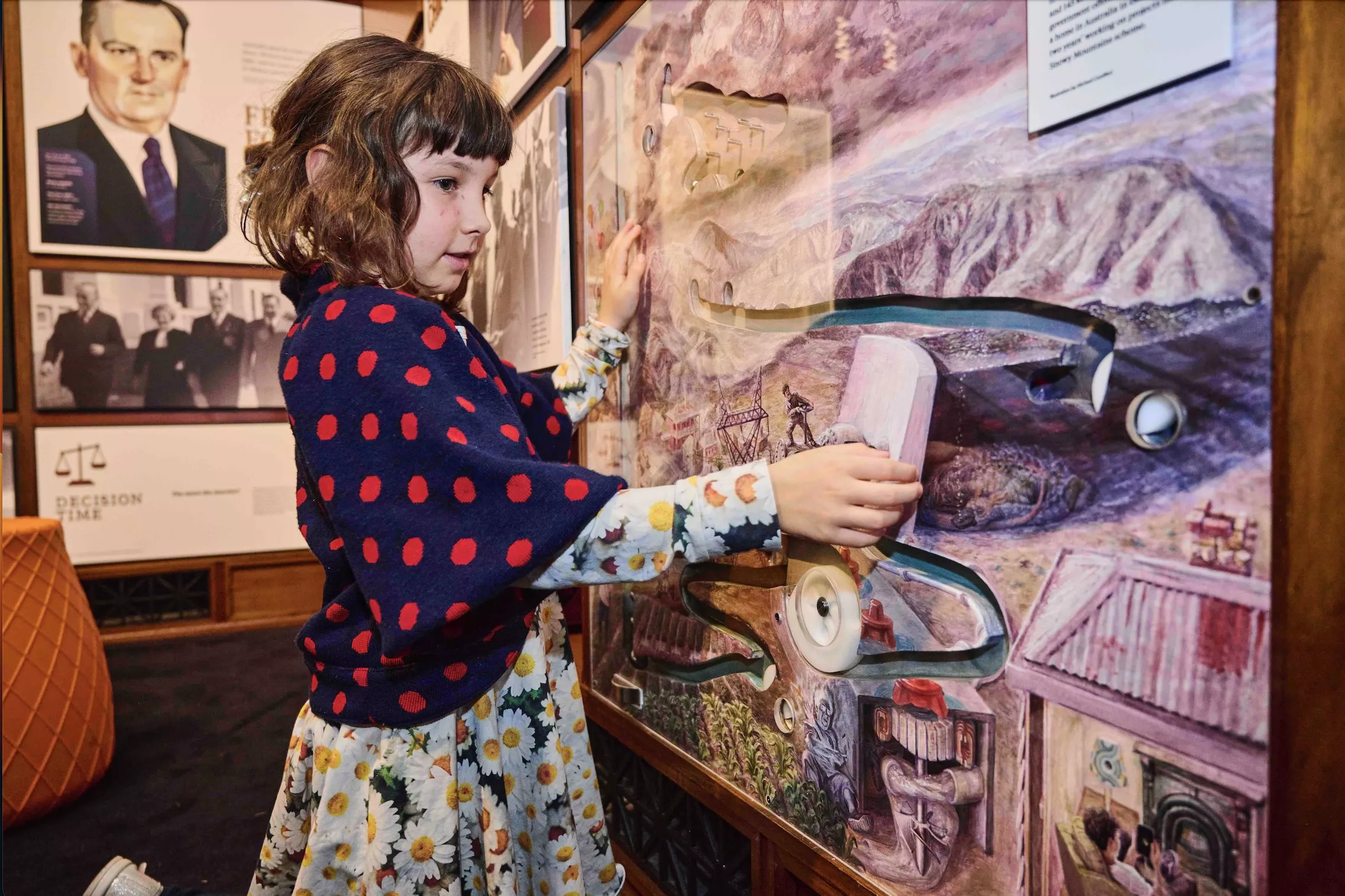 A young girl kneels on the floor and touches a marble display. A young girl kneels on the floor and touches a marble display.